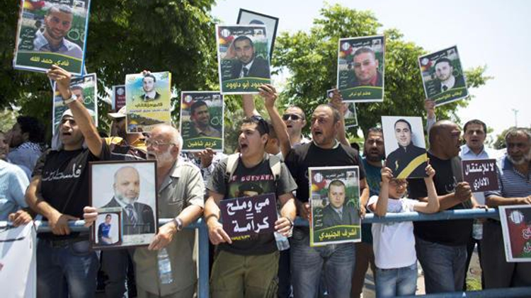 Palestinian activists hold placards during a protest outside the Israeli run Ayalon prison in Ramle, near Tel Aviv, calling for the release of Palestinian prisoners, on May 23, 2014, as they express solidarity with Palestinian prisoners who are on hunger